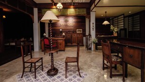A traditional wooden interior with a central table, chairs, and a lamp.