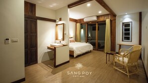 A bedroom with a wooden ceiling, a bed, a bedside table, a chair, and an air conditioning unit.