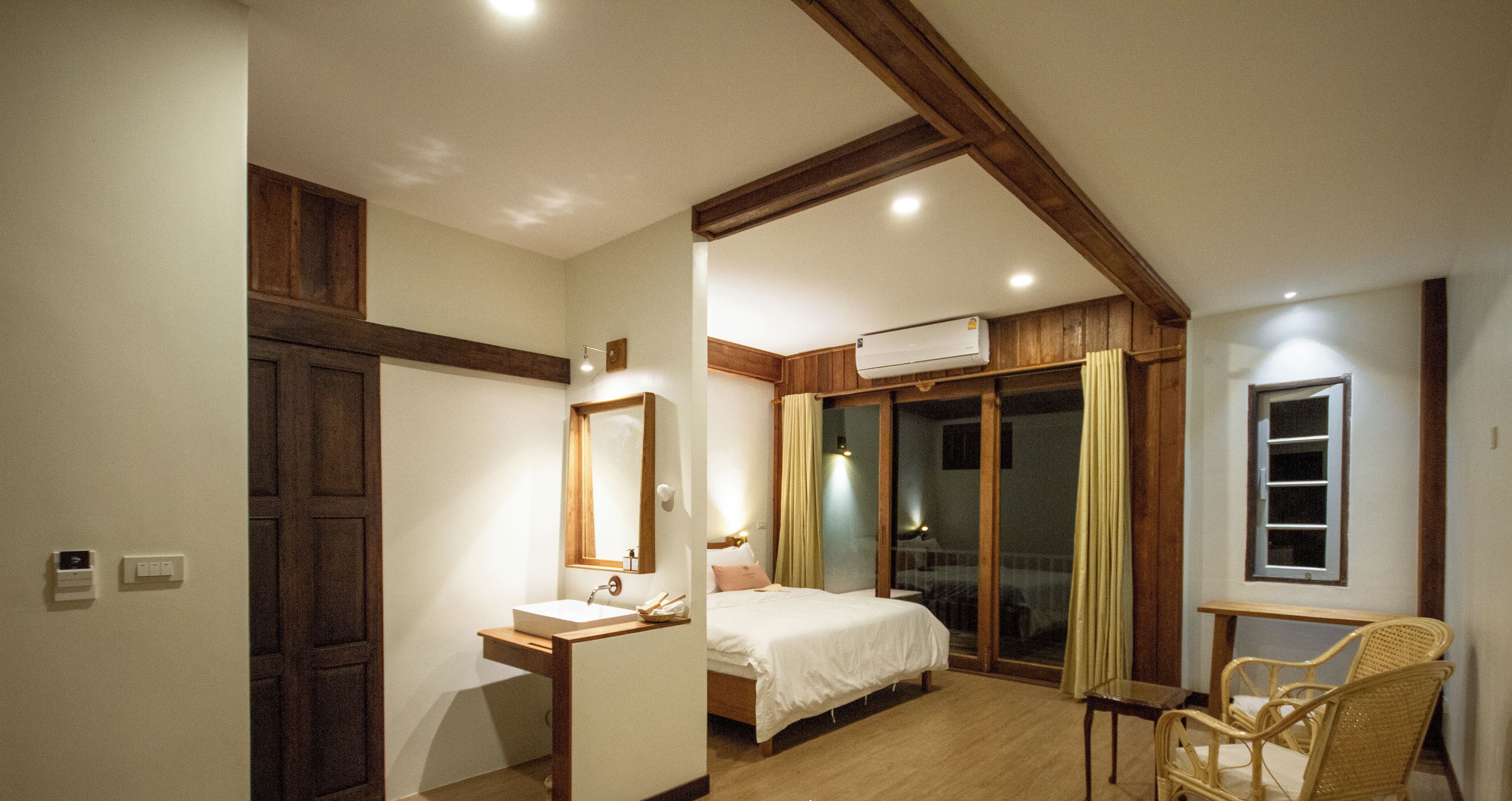 Un dormitorio con techo de madera, una cama, una mesita de noche, una silla y un equipo de aire acondicionado.