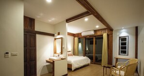 A bedroom with a wooden ceiling, a bed, a bedside table, a chair, and an air conditioning unit. - Sang Poy Cottage (Mae Hong Son)