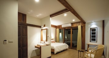Un dormitorio con techo de madera, una cama, una mesita de noche, una silla y un equipo de aire acondicionado.