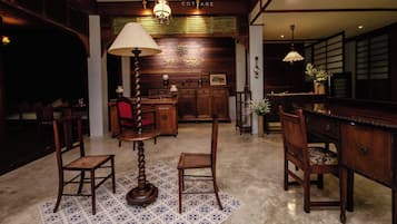 A traditional wooden interior with a central table, chairs, and a lamp.