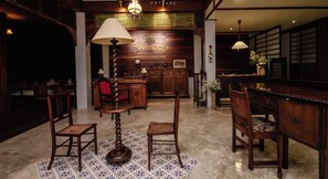 A traditional wooden interior with a central table, chairs, and a lamp. - Sang Poy Cottage (Mae Hong Son)