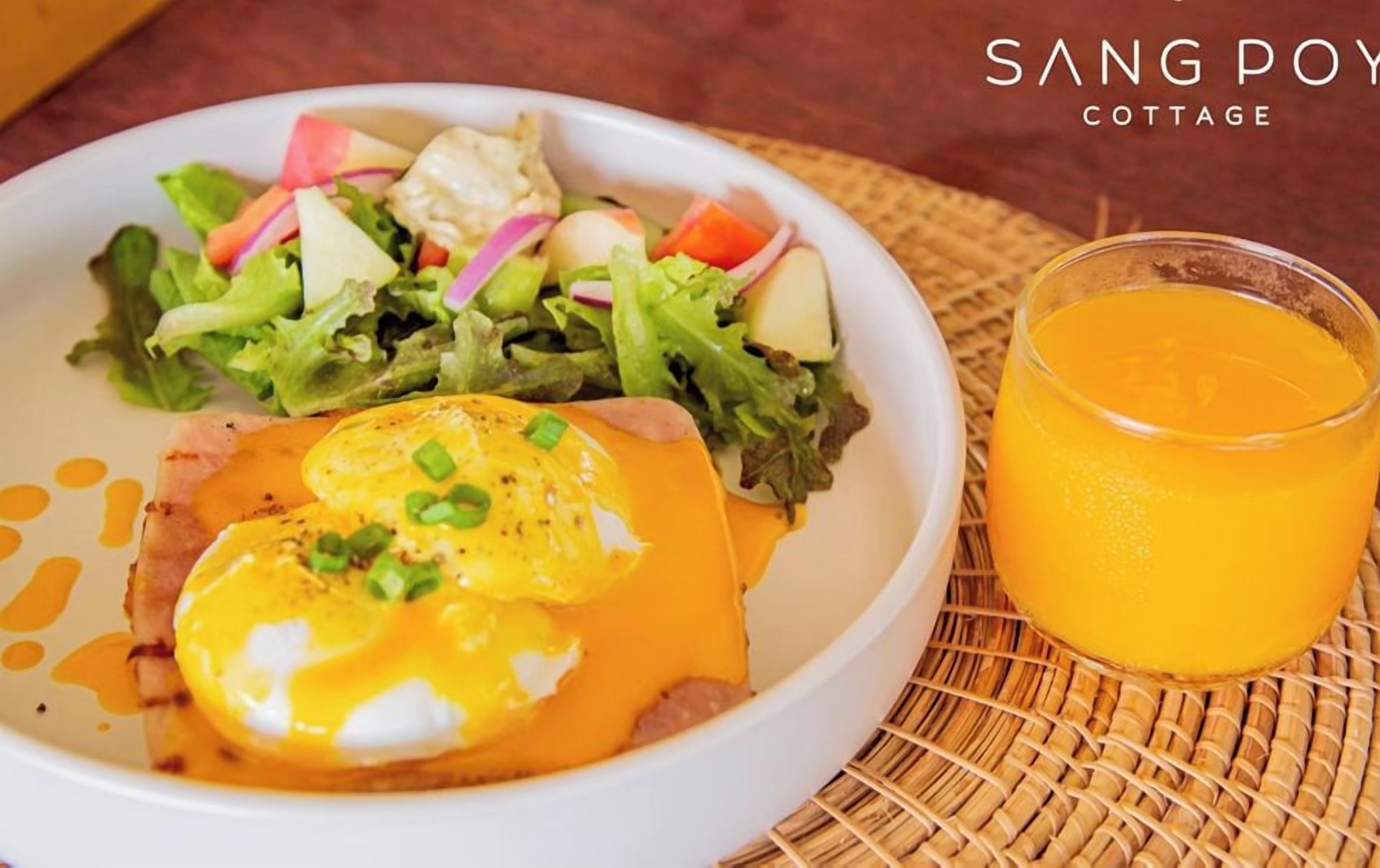Un plato de comida con un huevo escalfado, ensalada y un vaso de jugo de naranja.