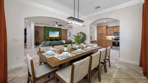 A dining area with a long wooden table set for six, surrounded by chairs. - Lakehouse Escape|Pool|HotTub|Game Suite|Sleeps 20 (Tampa)