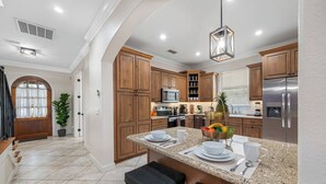 A modern kitchen with granite countertops, wooden cabinets, and stainless steel appliances. - Lakehouse Escape|Pool|HotTub|Game Suite|Sleeps 20 (Tampa)