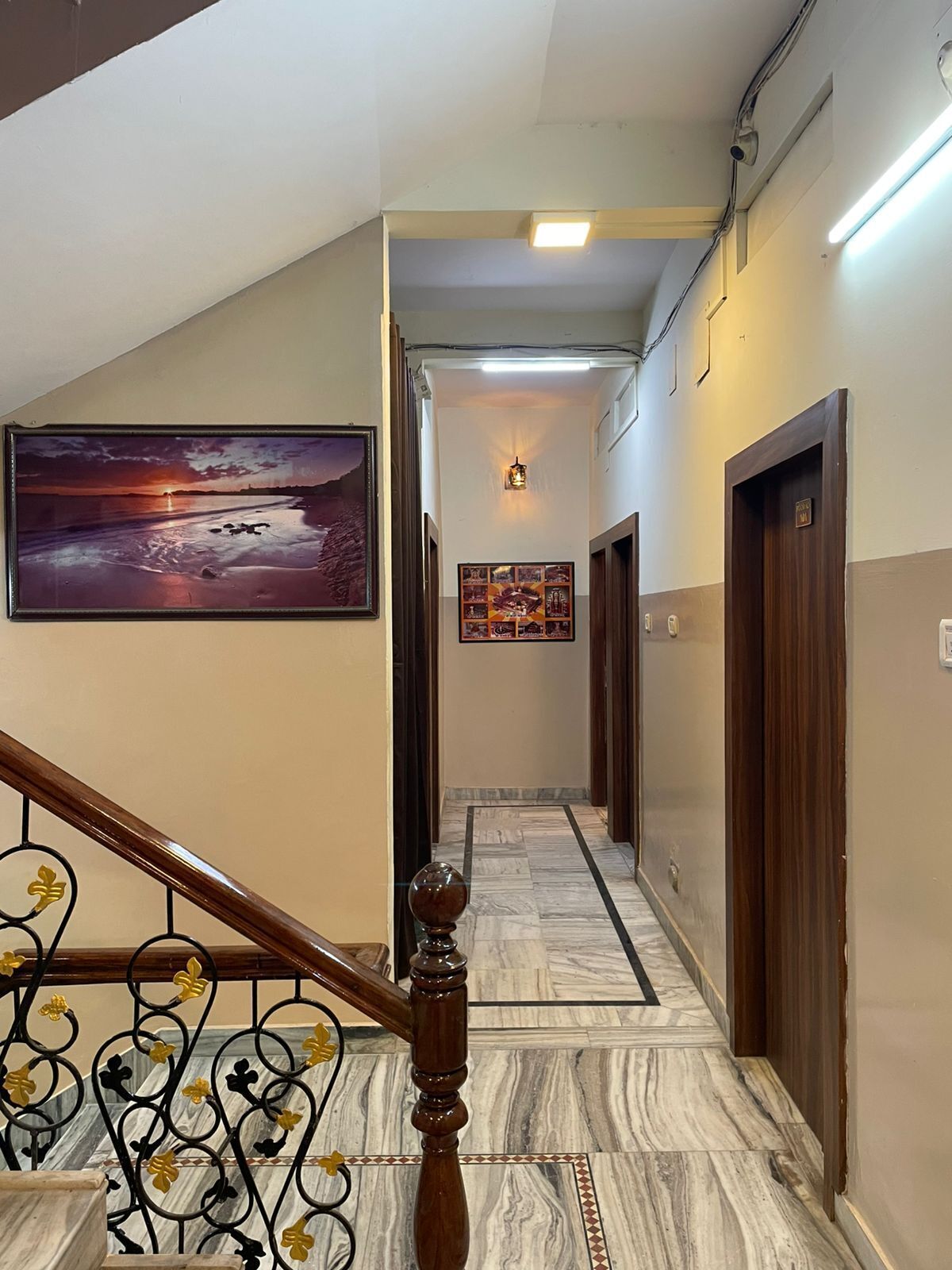 A hallway with a marble floor, a wooden staircase with a metal railing, and a wall-mounted picture.