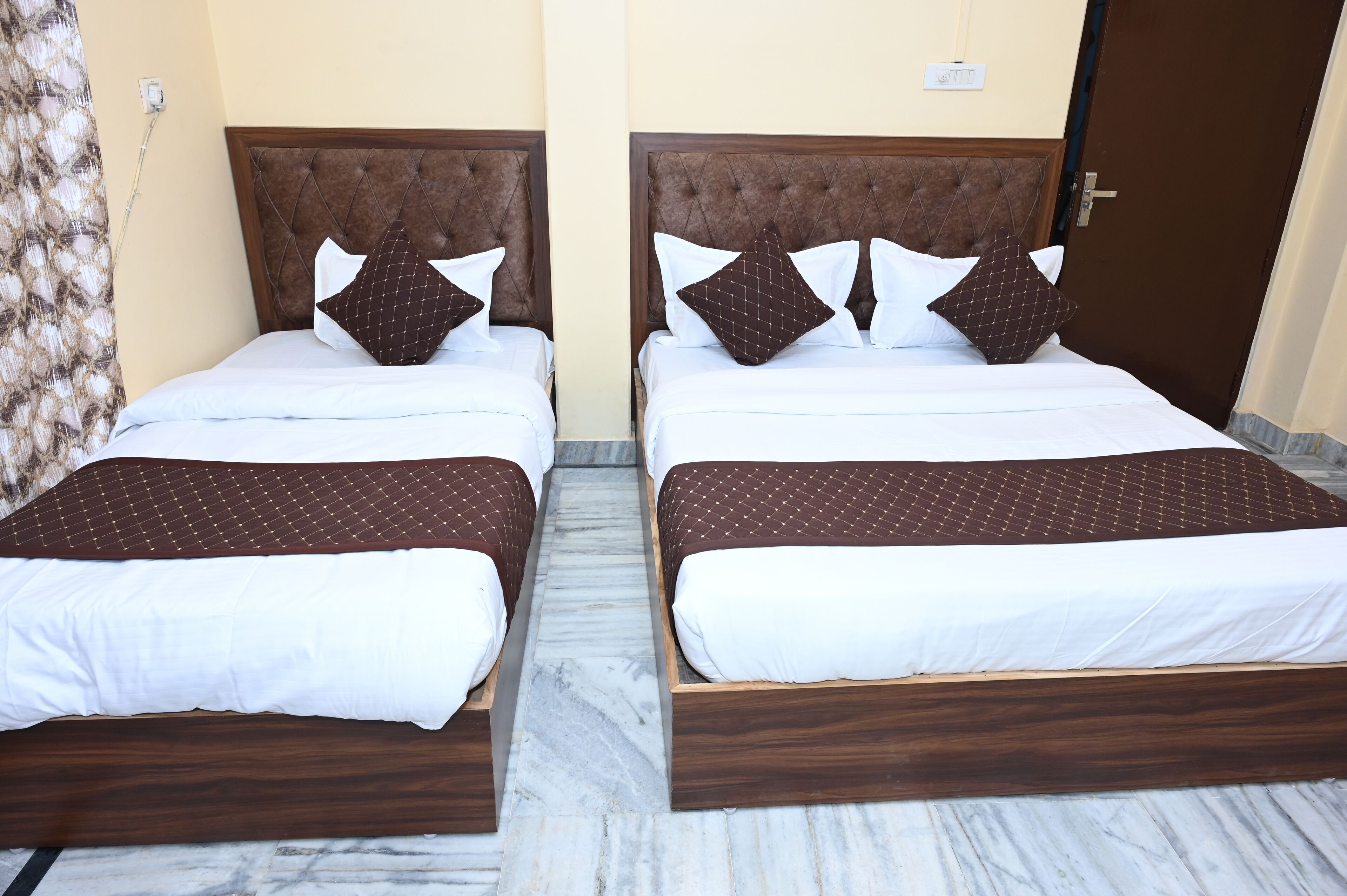 Dos camas individuales con cabeceros de madera, ropa de cama blanca y almohadas estampadas.