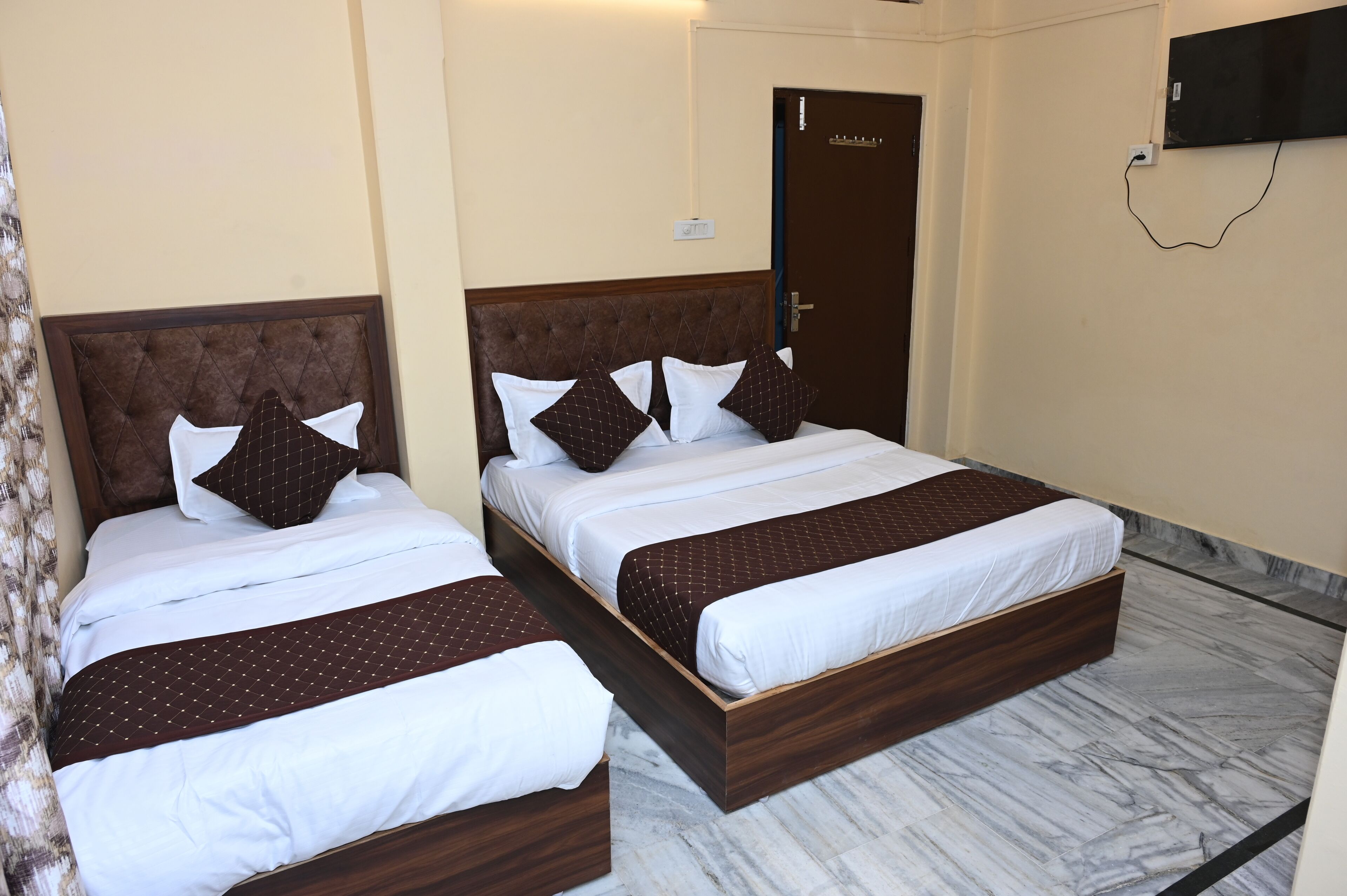 Une chambre d’hôtel avec deux lits, chacun doté d’une tête de lit en bois et de draps blancs.