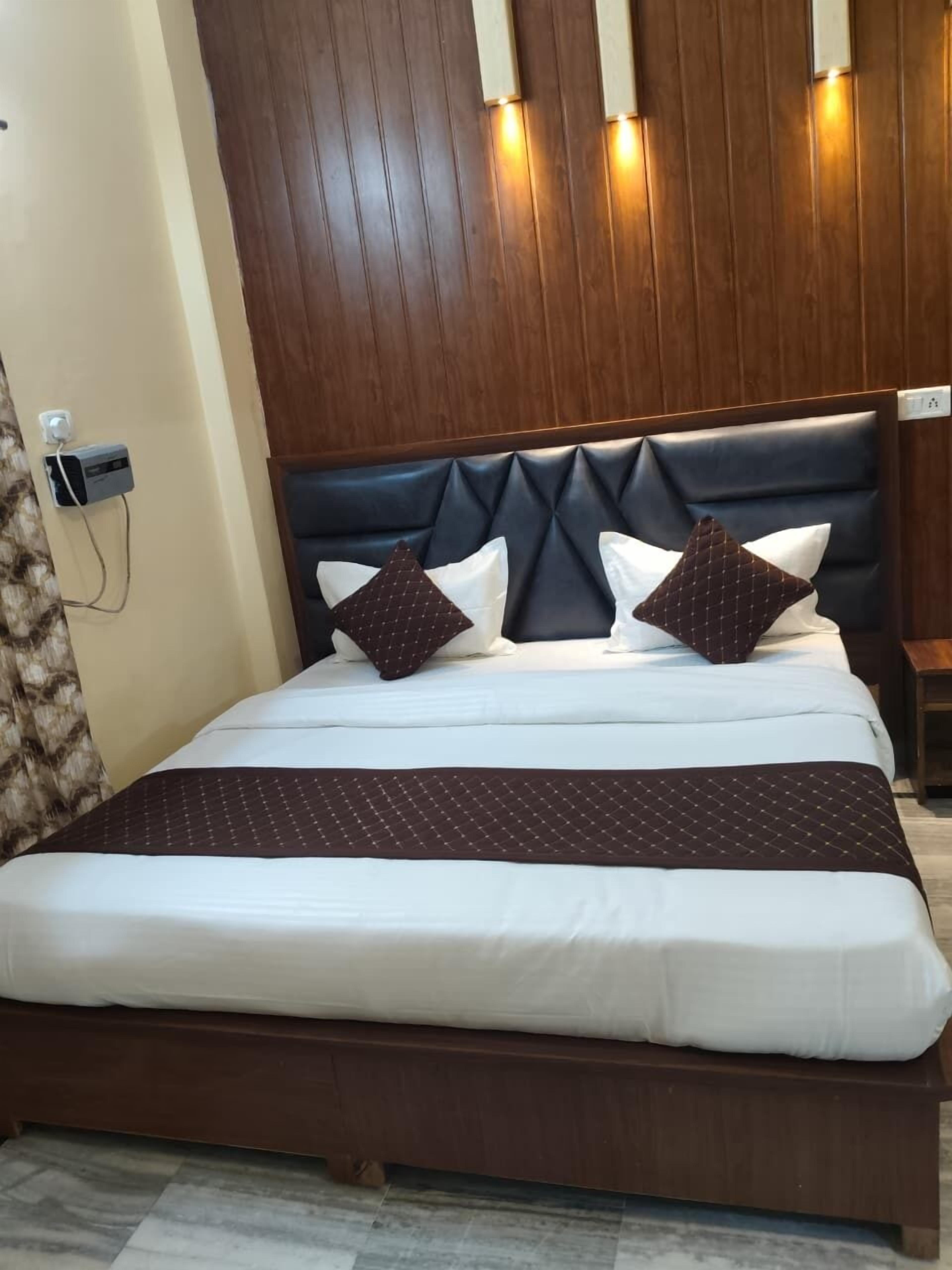 A bed with a dark headboard, white bedding, and two decorative pillows.