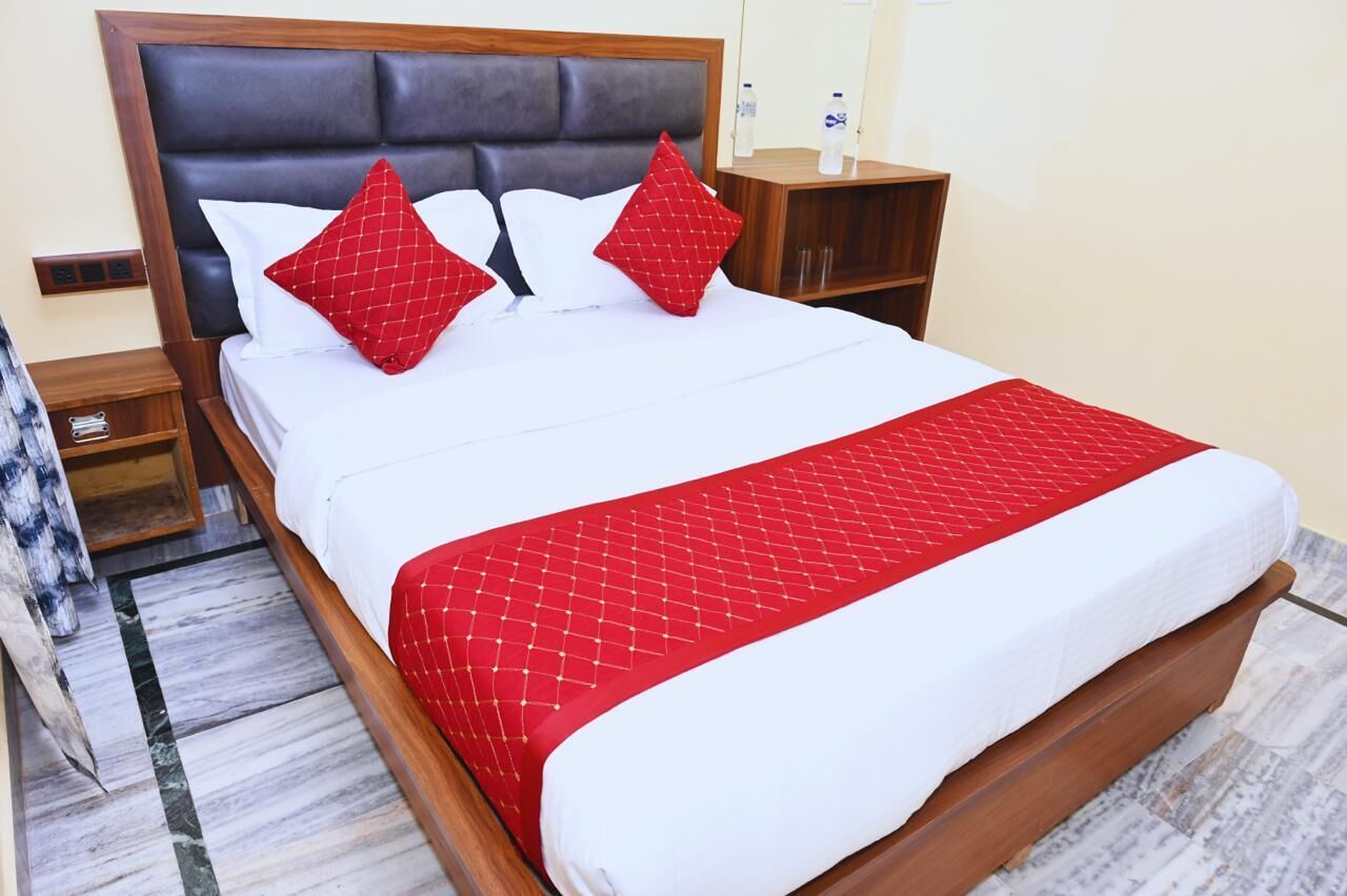 A neatly made bed with a red and white bedspread, a wooden headboard, and two bedside tables with lamps.