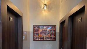 A hallway with two wooden doors, each marked with a room number. A framed collage hangs on the wall above the doors. - Hotel Heritage (Varanasi)