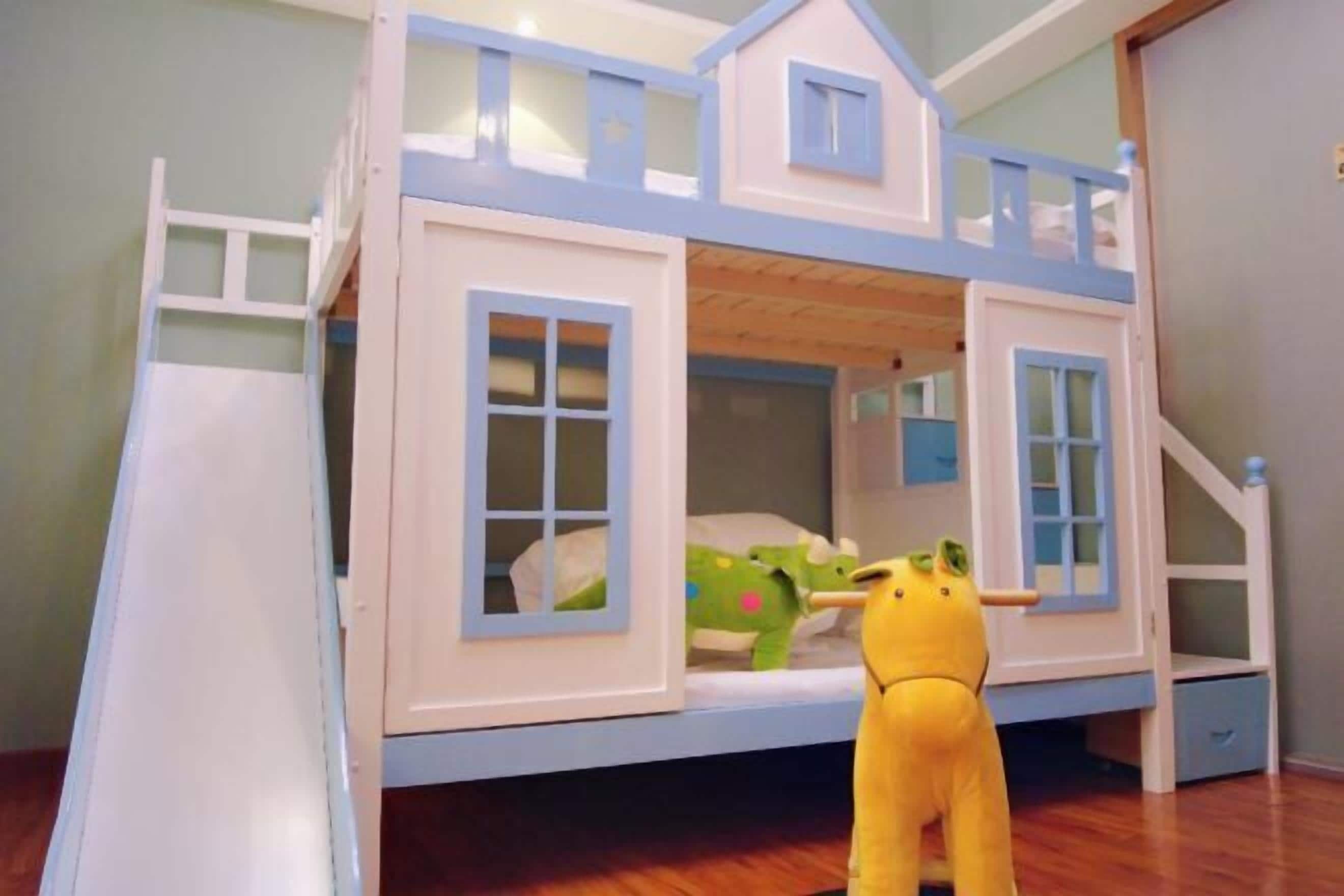 A bunk bed with a playhouse structure, a ladder, and a small storage drawer.