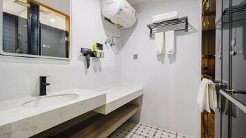 A modern bathroom with a white sink, a mirror, a towel rack, and a shower area.
