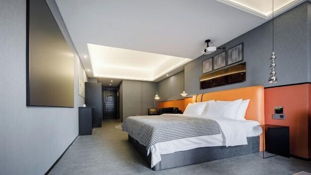 Ein modernes Schlafzimmer mit einem großen Bett, einer eingebauten Ablage und einem besonderen Deckengestalt.