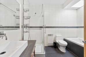 Un bagno moderno con doccia vetro, lavandino bianco, un water e una vasca da bagno.