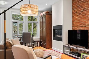 Un salon moderne avec une grande fenêtre, un téléviseur et une cheminée.