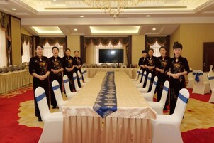 A conference room with a long table, white chairs, and a red carpet.