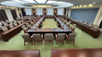 Uma sala de conferência com uma mesa comprida, várias cadeiras e piso coberto por carpete.