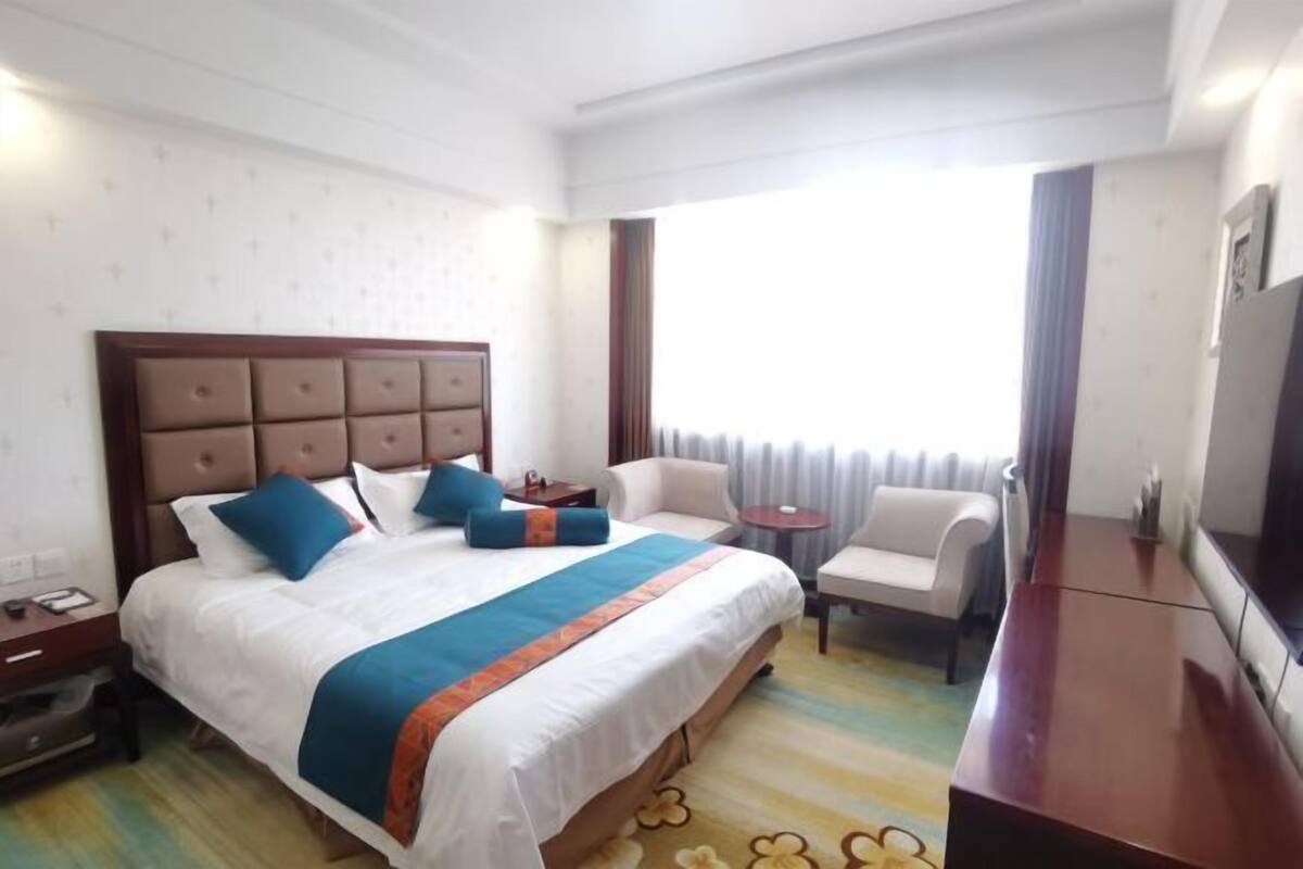 Une chambre d’hôtel avec un grand lit, une petite table, une chaise et un téléviseur.