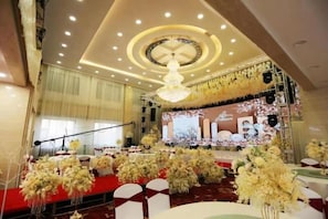 Un espace événementiel intérieur doté d’une scène, d’un tapis rouge, de compositions florales et d’un lustre.