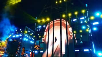 A large cylindrical structure with a person standing in front of it, surrounded by stage lighting and equipment.