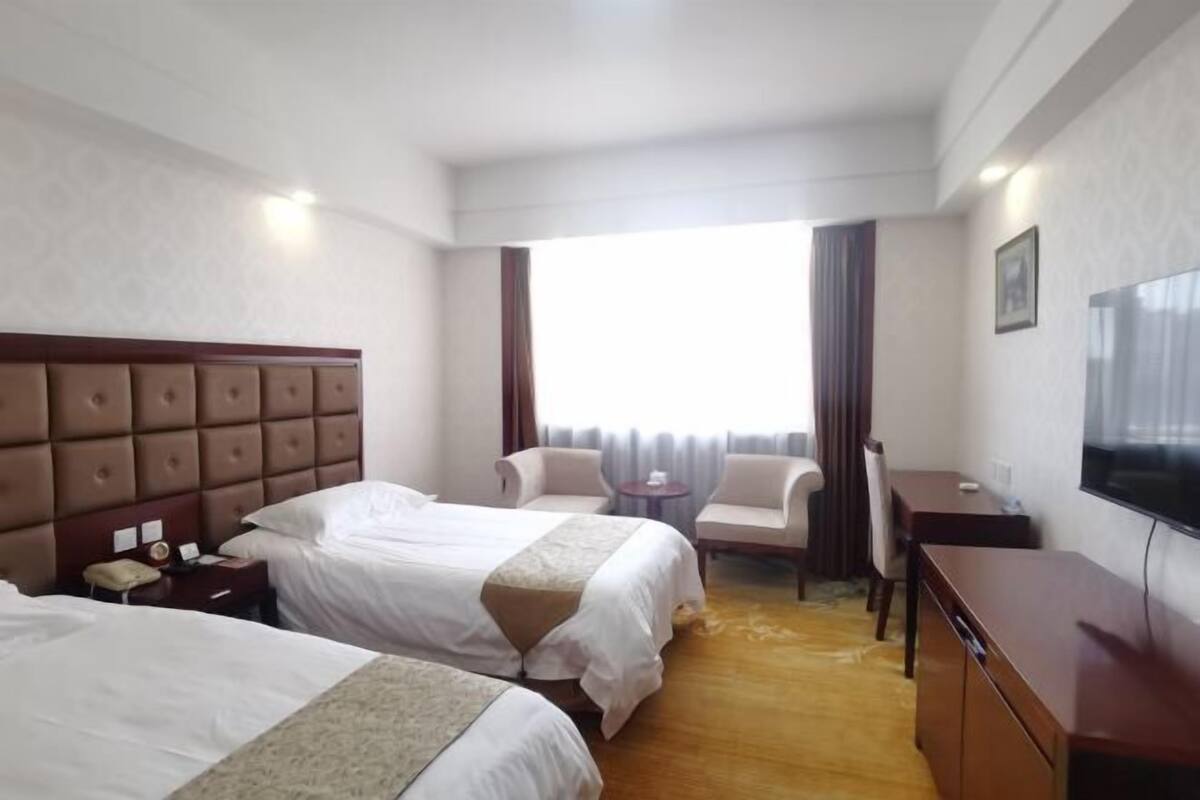 Une chambre d’hôtel avec deux lits, une télévision, un bureau et une chaise.