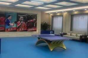 Ein Raum mit Tischtennisplatte, einer Couch und einem großen Poster an der Wand.