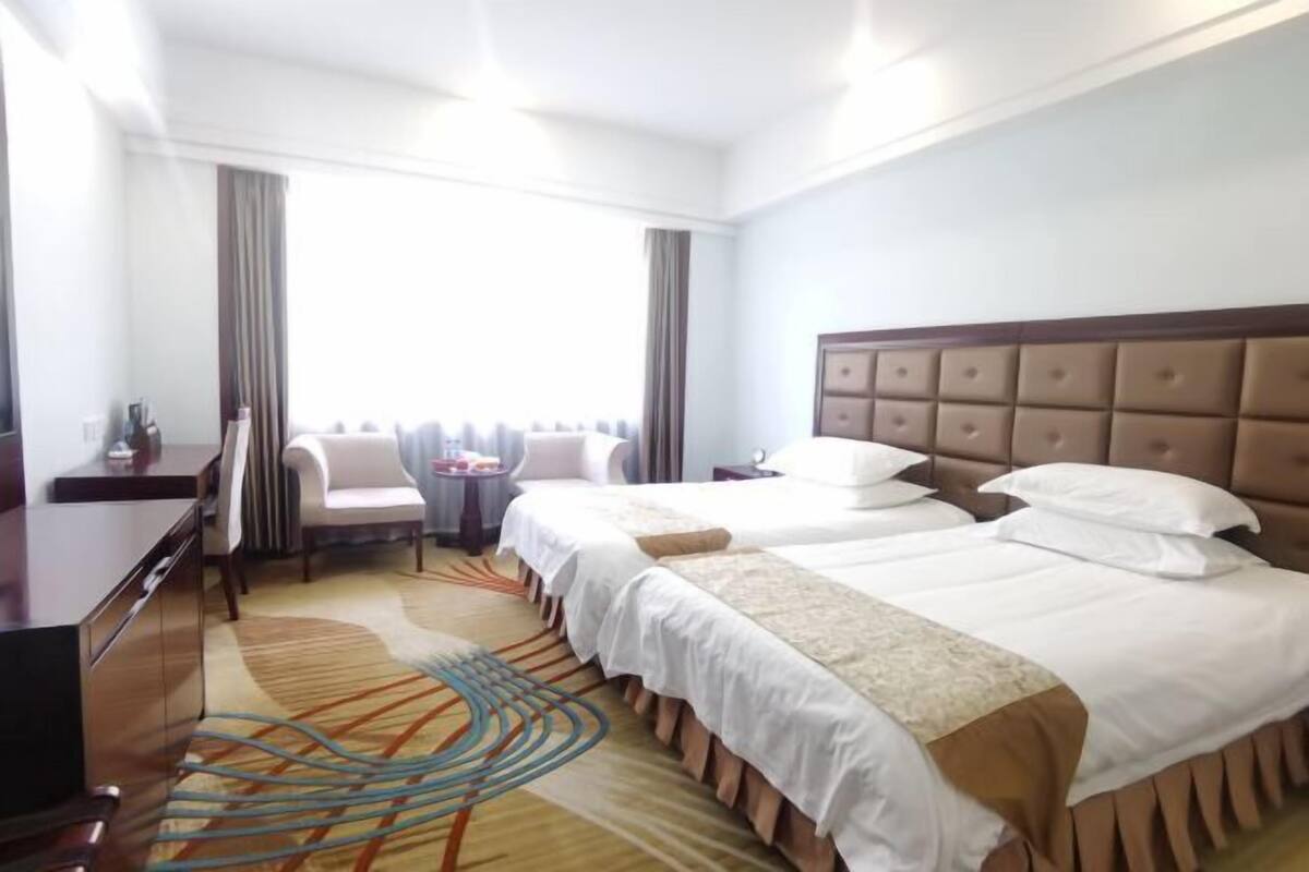 Une chambre d’hôtel avec deux lits, un bureau, une chaise et une vue sur la ville.