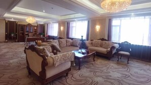 Un salon spacieux agrémenté d’un grand lustre, de canapés et d’un tapis à motifs.
