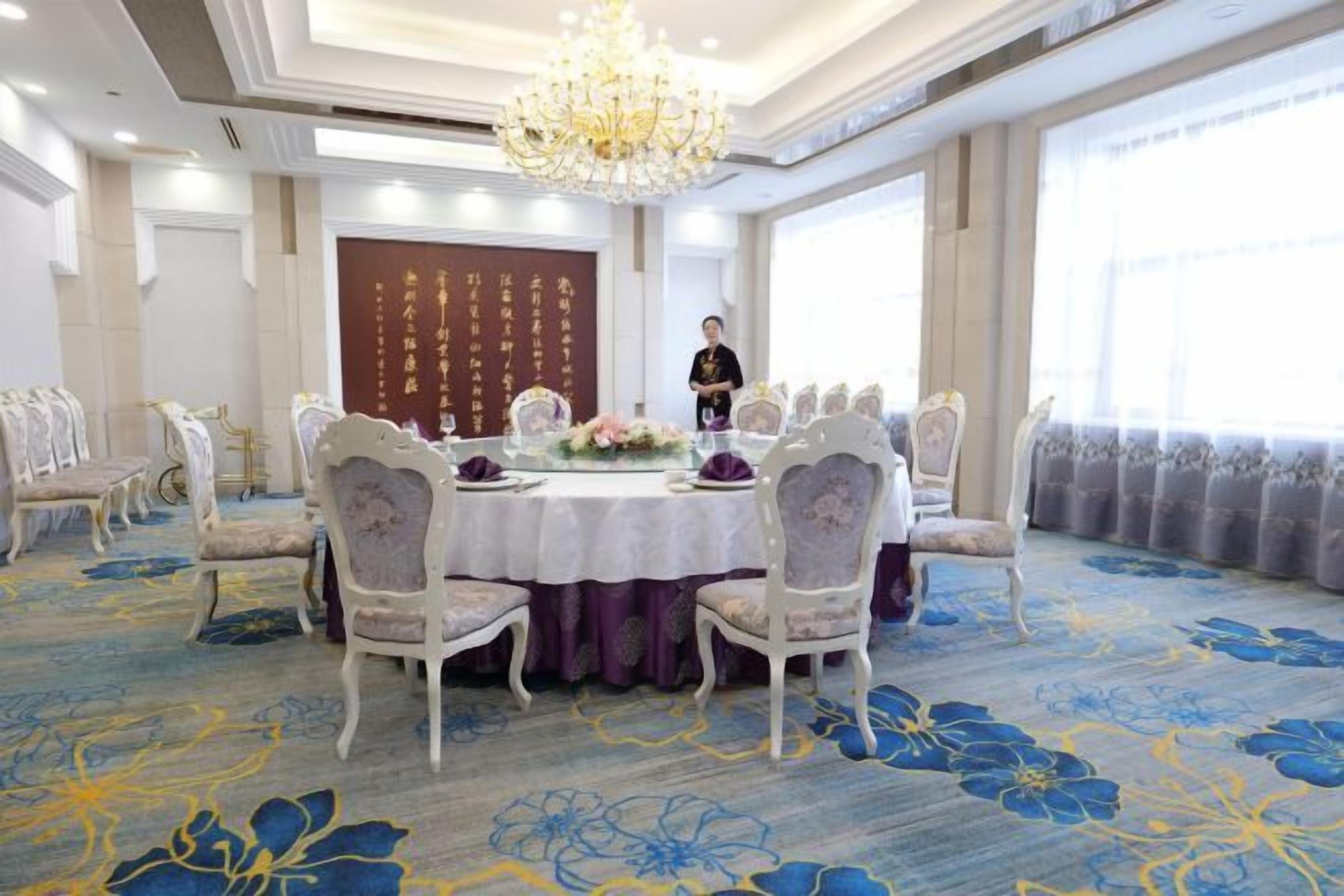 A conference room with a round table, chairs, and a chandelier.