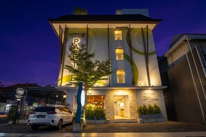 Egy modern hotel, amelyen feltűnő „P” betűvel jelölték a parkolóhelyet, jól látható bejárattal és világosan megvilágított homlokzattal rendelkezik.