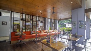 A restaurant with wooden flooring, a red sofa, and metal chairs. - Palette Hotel near Padma (Legian)