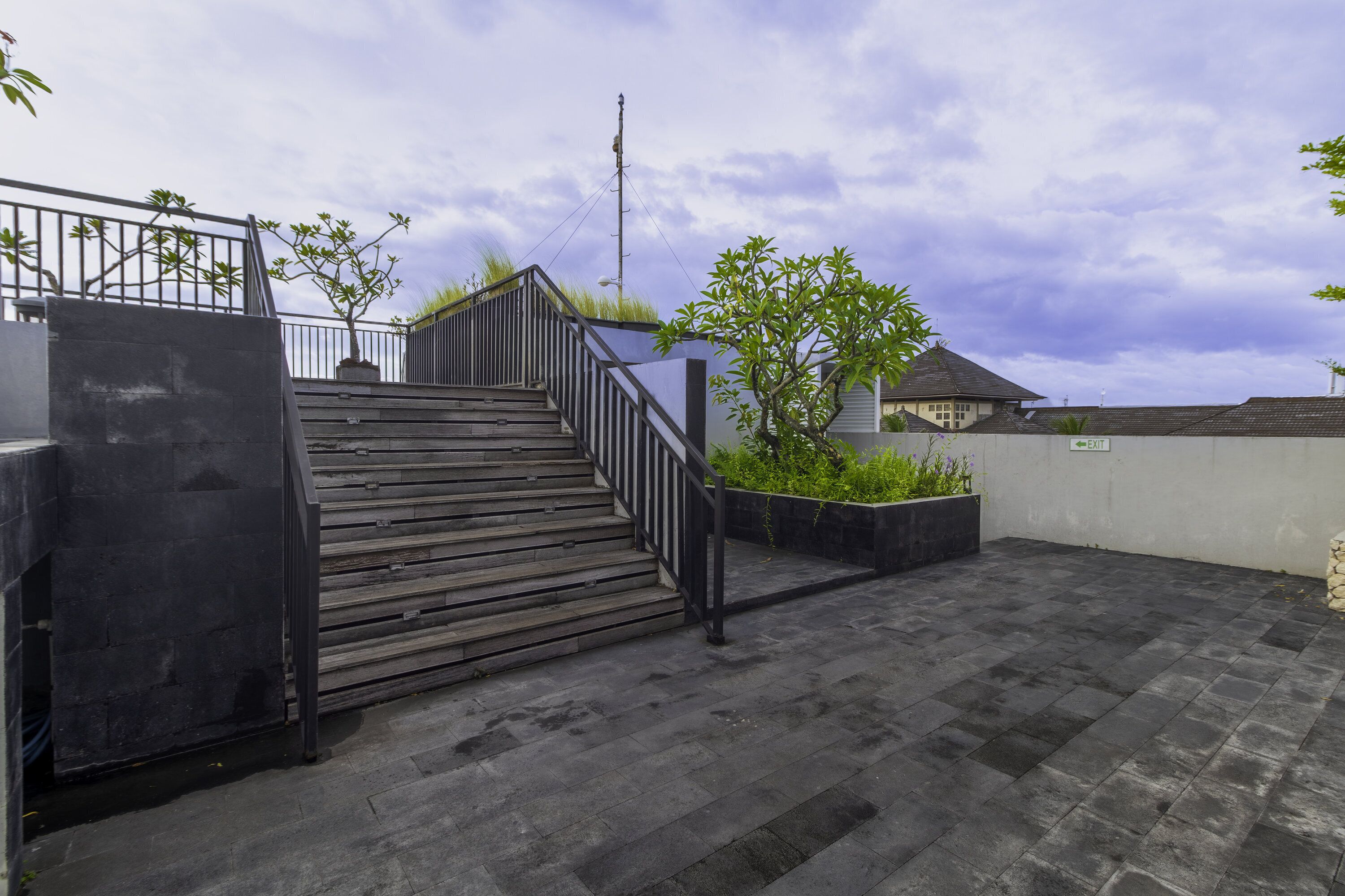 Une terrasse sur le toit, avec un escalier en bois, une rambarde en métal et une vue sur le ciel.