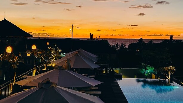 A resort with a swimming pool, umbrellas, and a view of the sunset over the ocean. - Palette Hotel near Padma (Legian)