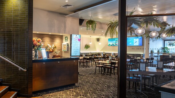 A hotel lobby with a reception desk, seating area, and a large window with a view.
