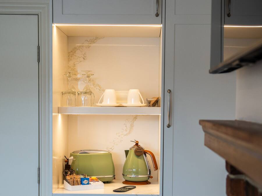 Una cocina con encimera de mármol, un hervidor verde, una cafetera y un control remoto.