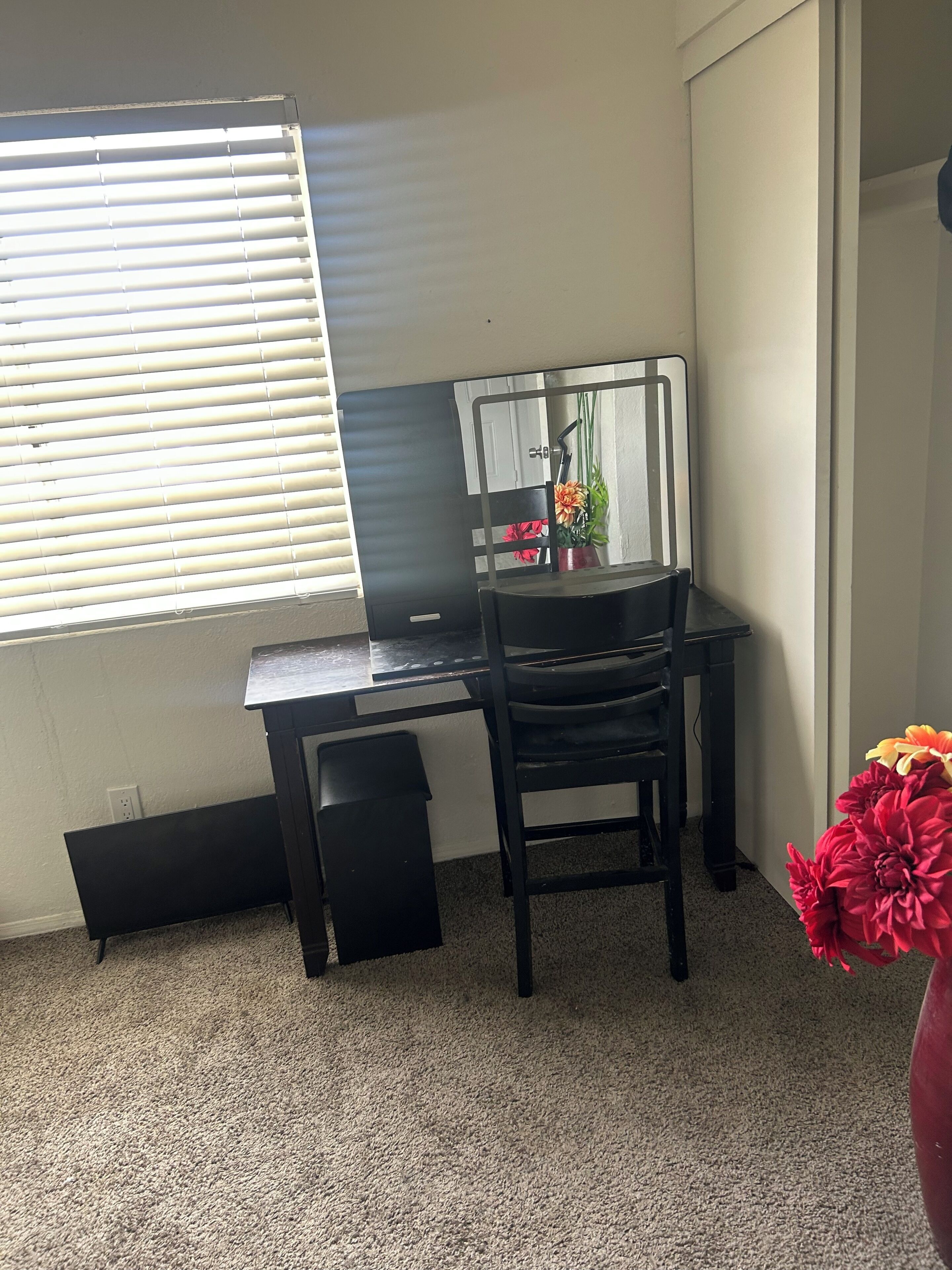 A room with a desk, chair, and a window with blinds.