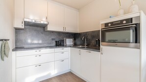 Eine moderne Küche mit weißen Schränken, einer Edelstahl-Dunstesse, einer eingebauten Mikrowelle und einem Edelstahl-Backofen.