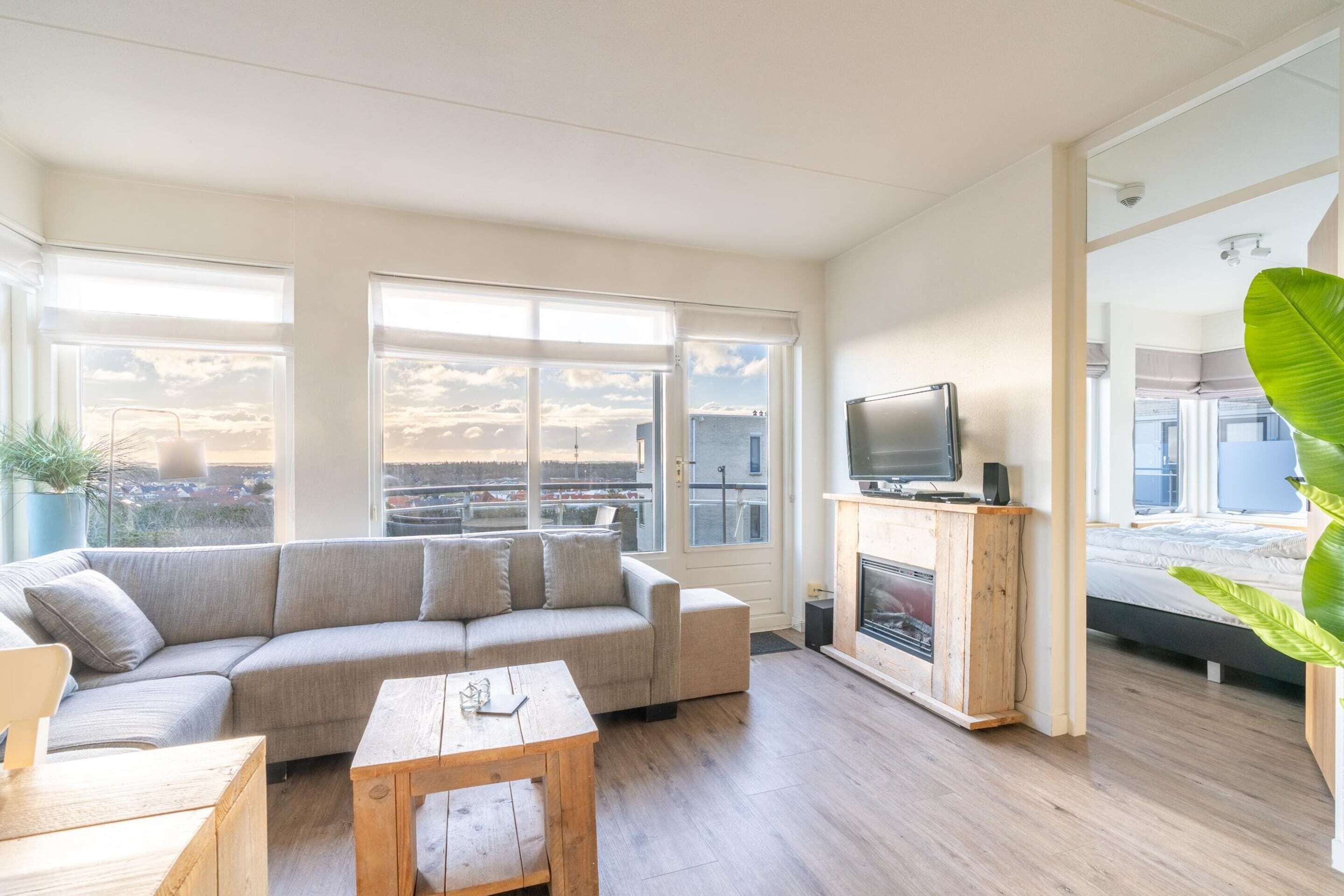 Ein stilvolles Wohnzimmer mit einer großen Couch, einem Holztisch, einem Kamin und einem Fernseher.