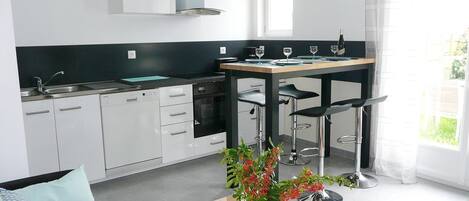 A modern kitchen with white cabinets, a black countertop, and a dining area with bar stools.
