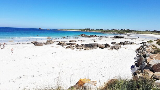 A beach with white sand, clear blue water, and scattered rocks. - Apartment in Lilia Near Kastell Ac"h Strand (Plouguerneau)