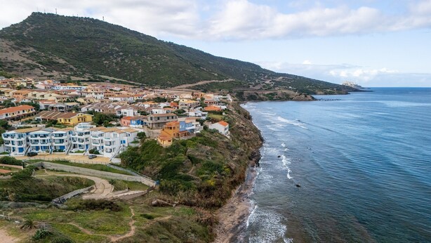 A coastal town with buildings along the shore, a mountain in the background, and a clear view of the sea. - 150 Meters From the Sea, 2 Swimming Pools (Valledoria)