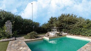 A swimming pool with stone tiles, surrounded by greenery and a stone structure. - 150 Meters From the Sea, 2 Swimming Pools (Valledoria)