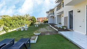 A modern building with a well-maintained lawn, outdoor seating, and a clear sky. - 150 Meters From the Sea, 2 Swimming Pools (Valledoria)