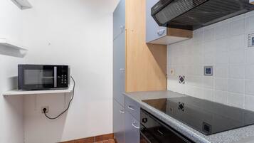 Een koelkast, een microgolfoven, een oven, kookgerei, borden en bestek