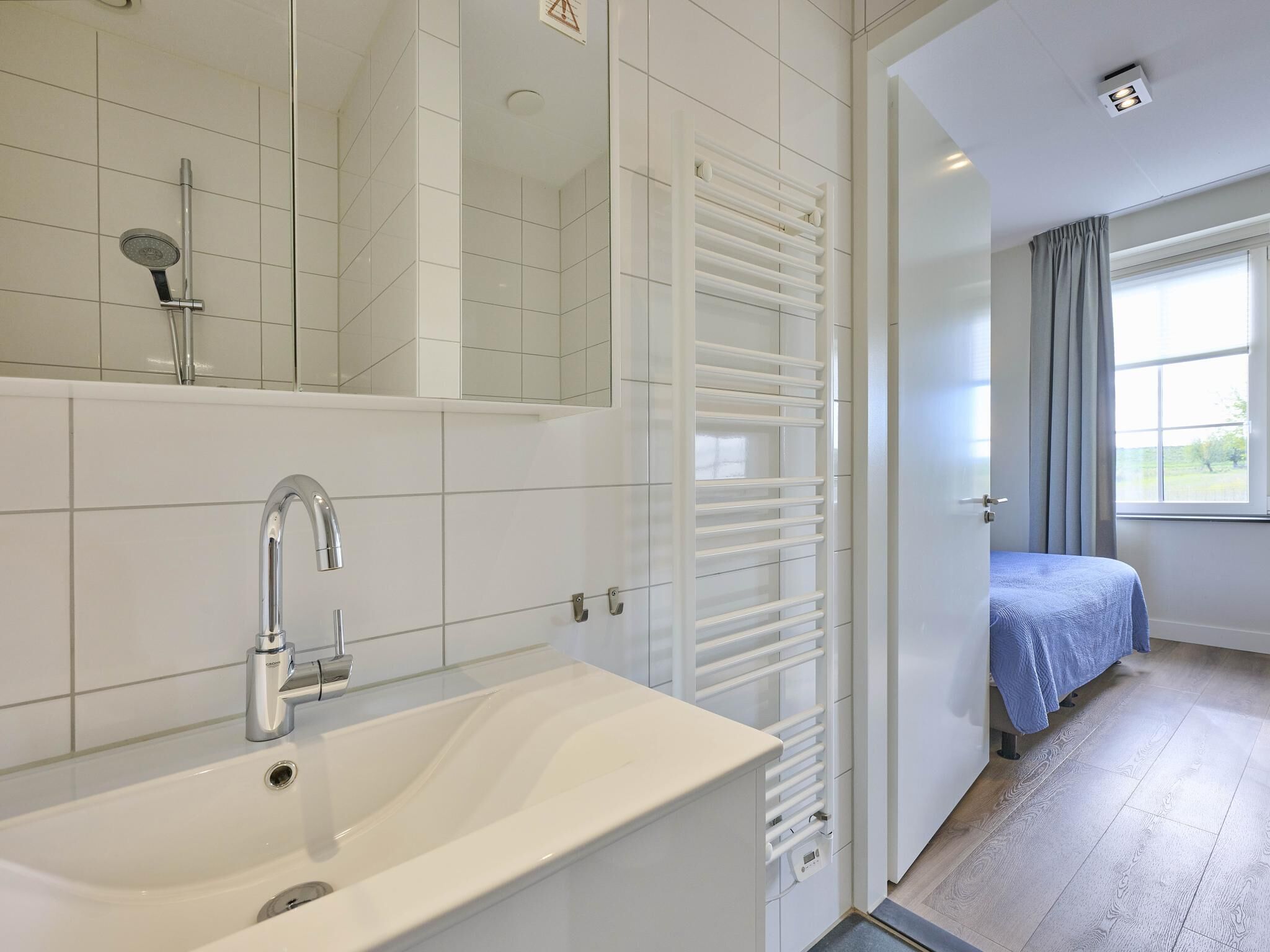 A modern bathroom with a white sink, a shower, and a built-in heater.
