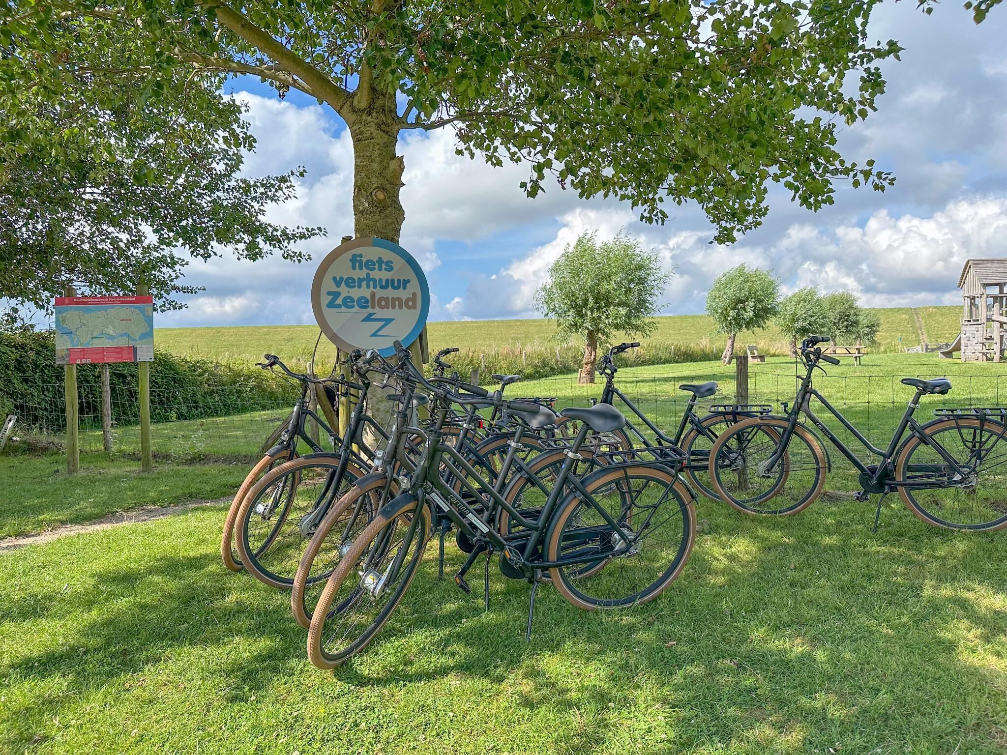 Skilt for Fiets Verhuur Zeeland med cykler parkeret i nærheden.