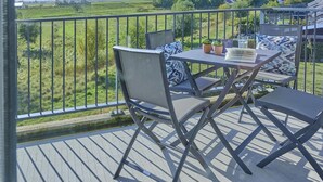Ein Balkon mit Tisch und Stühlen, mit Blick auf eine grüne Landschaft.