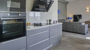 Eine moderne Küche mit integrierten Geräten, einer grauen Arbeitsplatte und einem grauen Sofa im Wohnbereich.